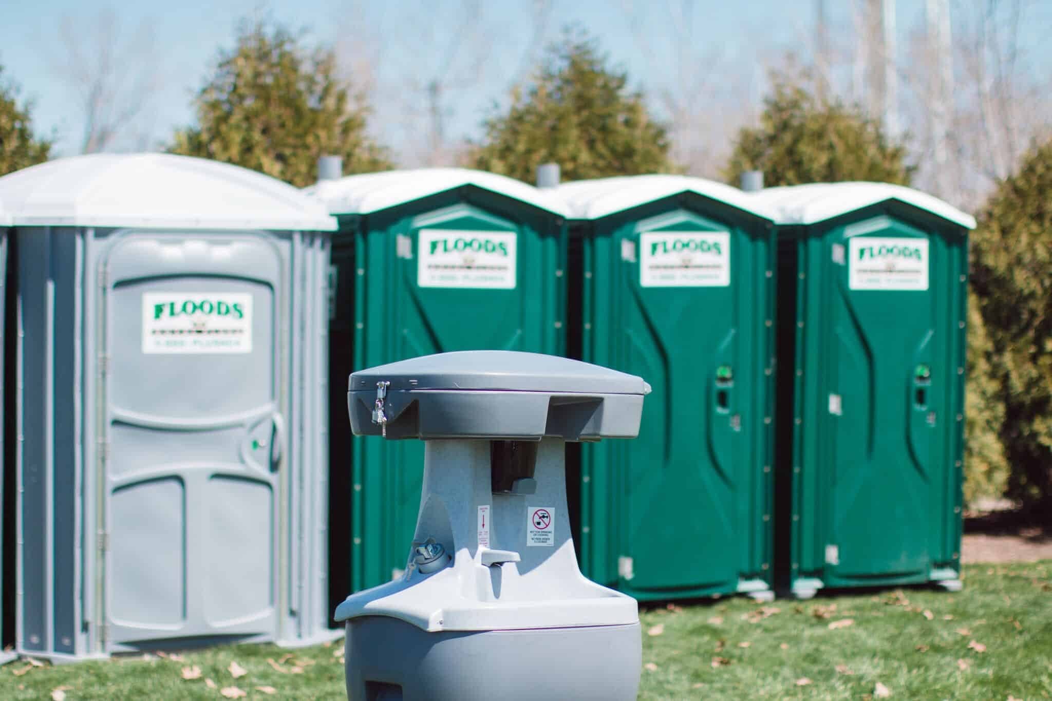 Floods Royal Flush hand wash station in front of a row of green portable restrooms