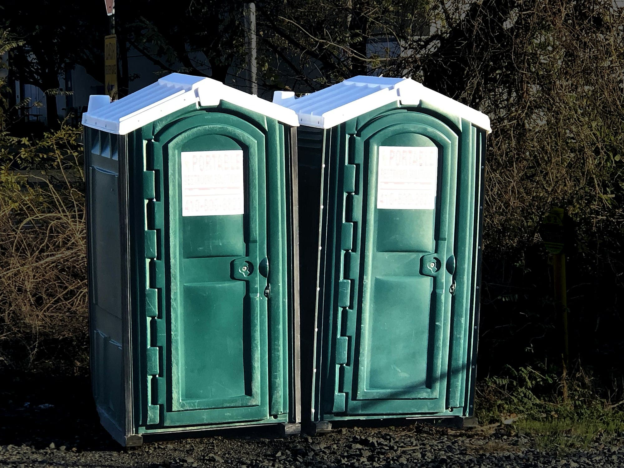 Two clean green portable restrooms in a field